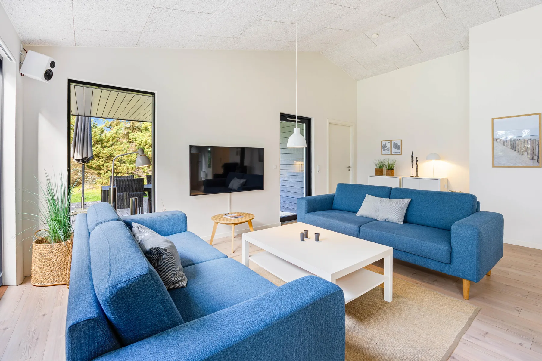 Una sala luminosa con asientos azules y una mesa de centro blanca.