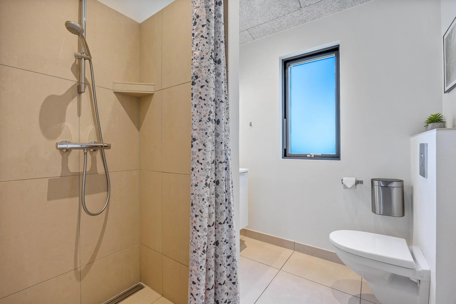 Un baño con ducha, inodoro y ventana.