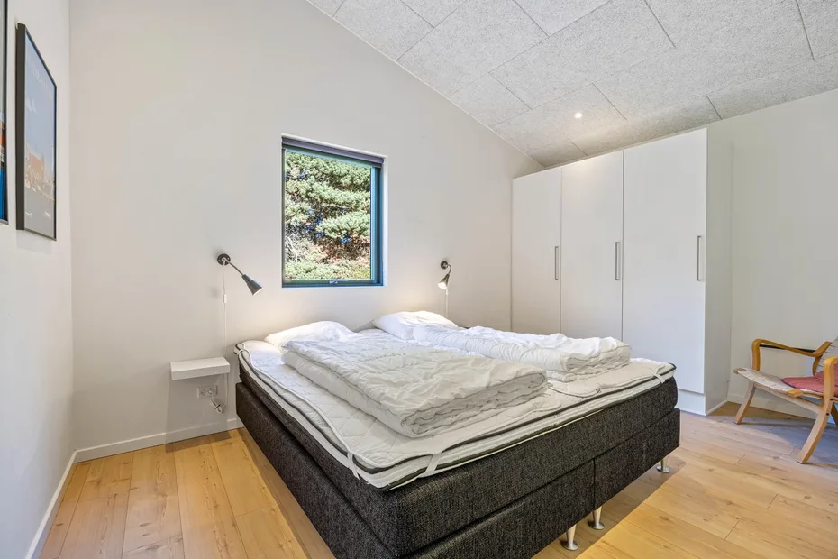 Un dormitorio con una cama, ropa de cama blanca y armarios empotrados.