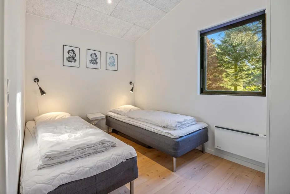 Un dormitorio con dos camas, lámparas de pared y una ventana con vistas a los árboles.