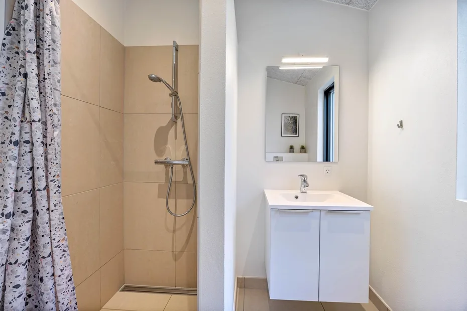 Un baño con ducha, lavabo y espejo de pared.