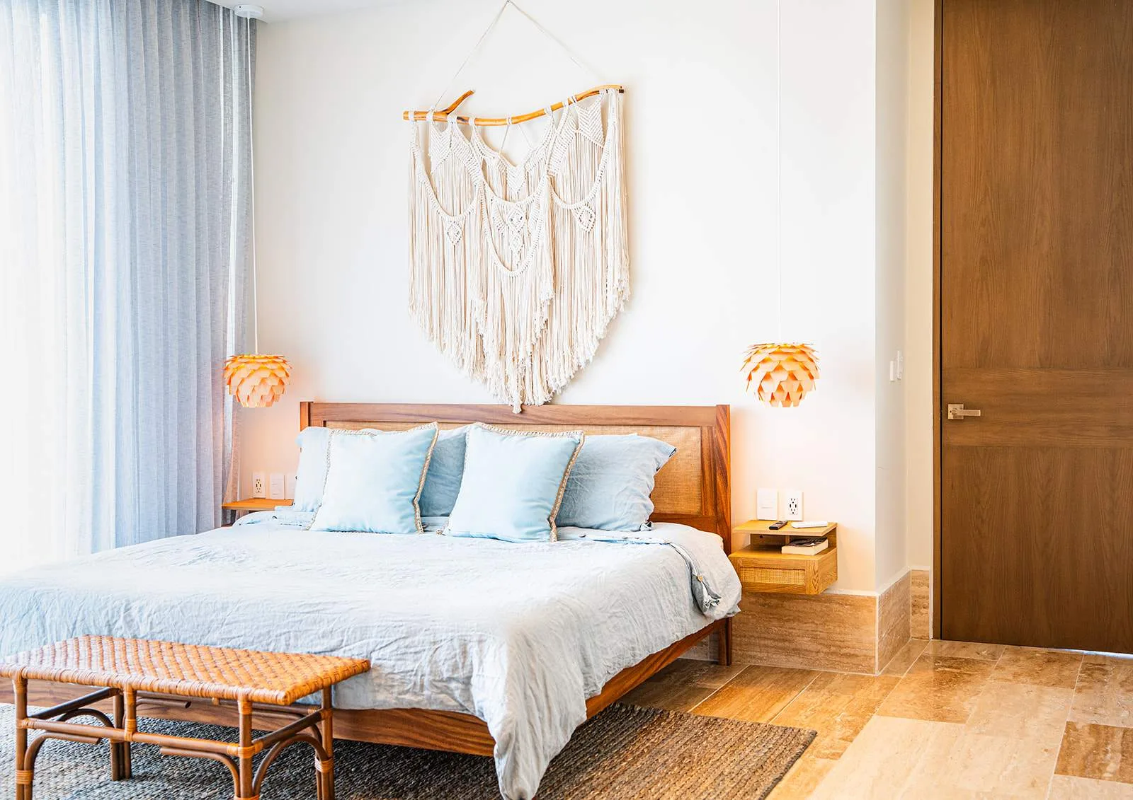 Un dormitorio con una cama, ropa de cama azul claro y un tapiz tejido.