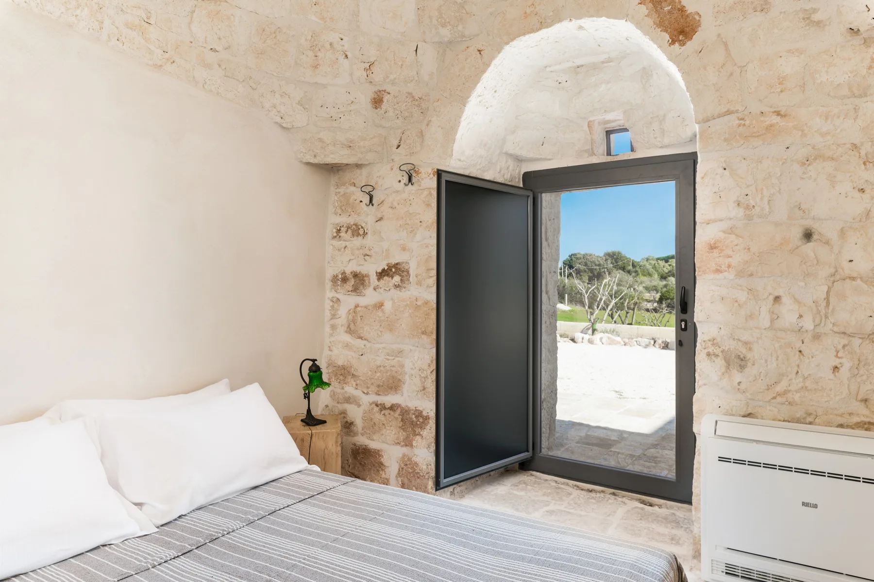 A bedroom with a bed beside an open doorway leading outdoors.