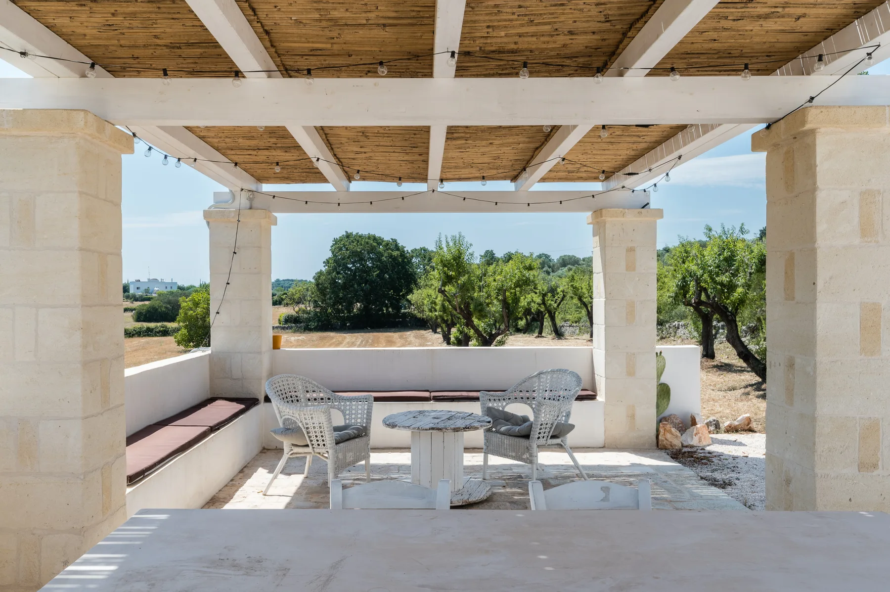A covered outdoor seating area with a table and views of trees.