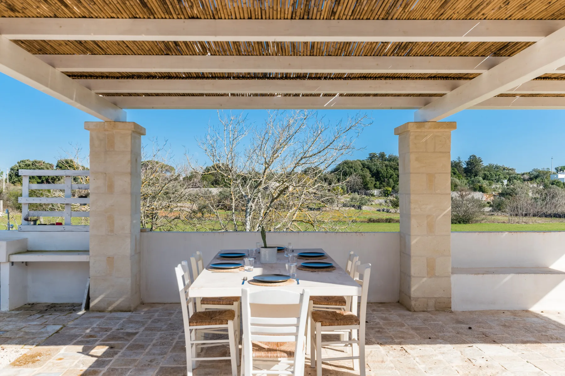 A covered outdoor dining area with a table set beneath a wooden pergola.
