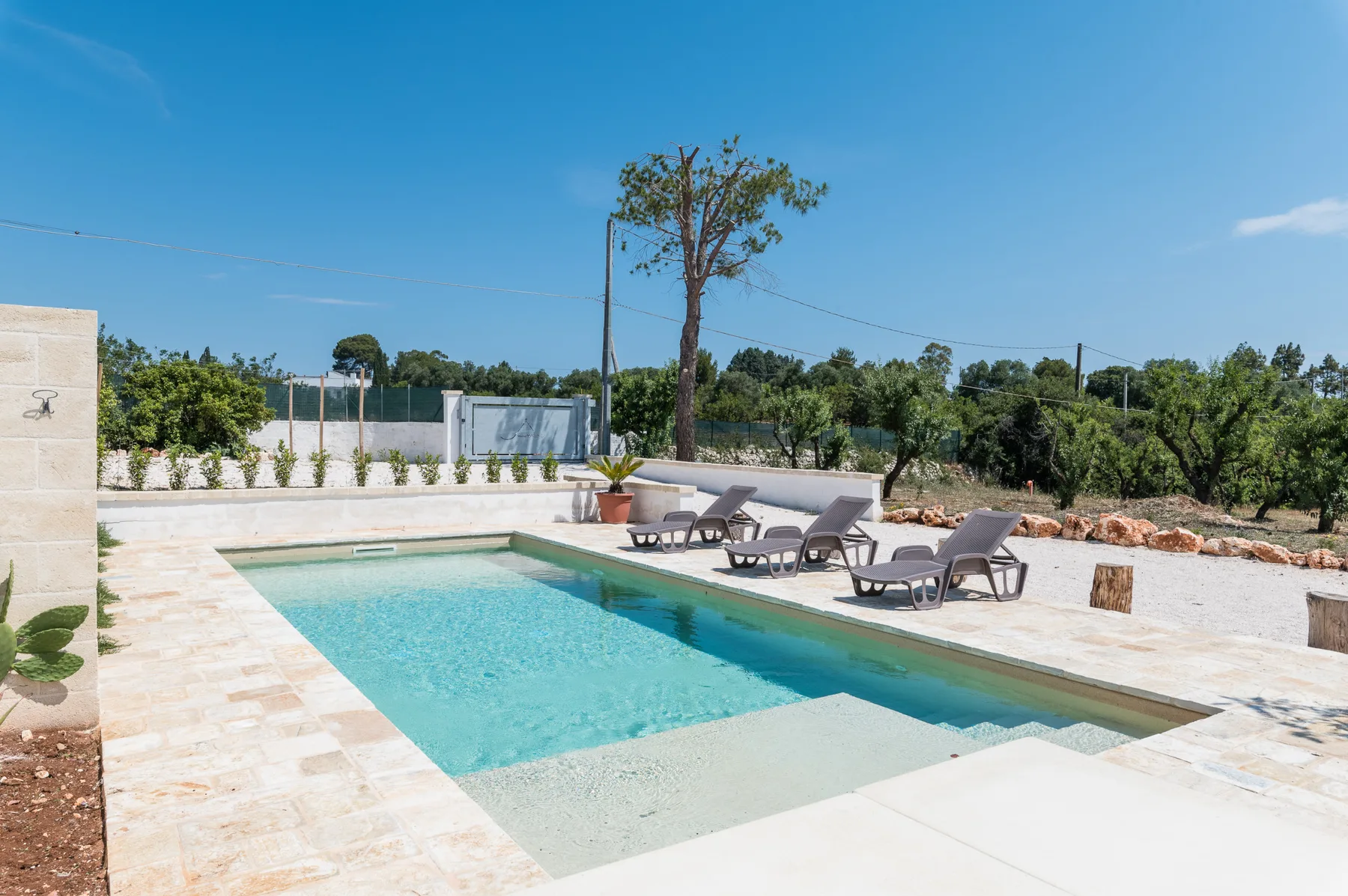 Outdoor swimming pool beside a paved patio with lounge seating.