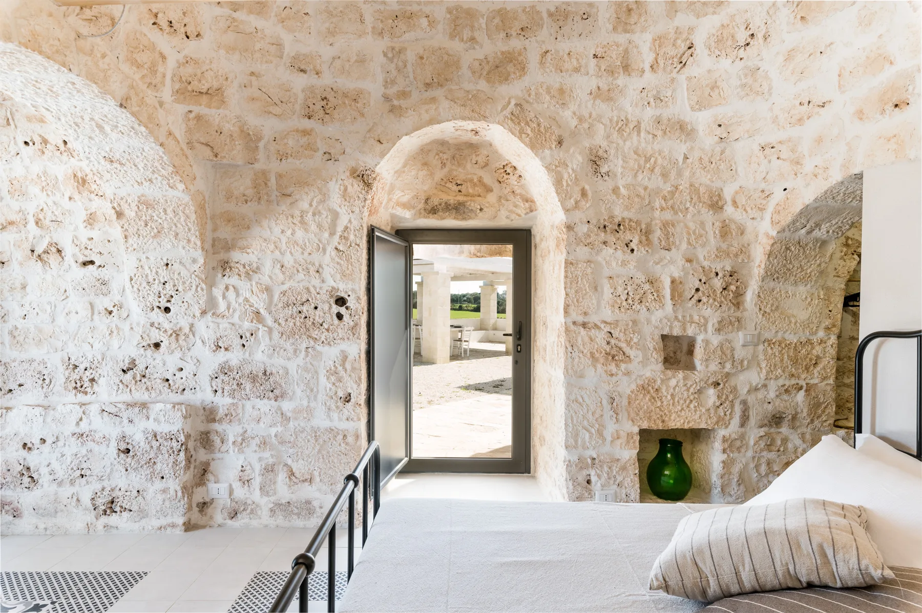 A stone bedroom with a bed beside an open doorway.