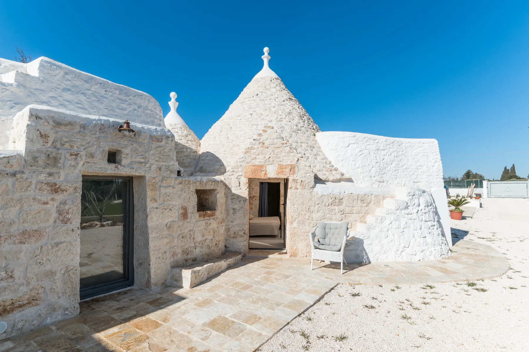 White stone buildings with conical roofs surround a sunlit paved courtyard.