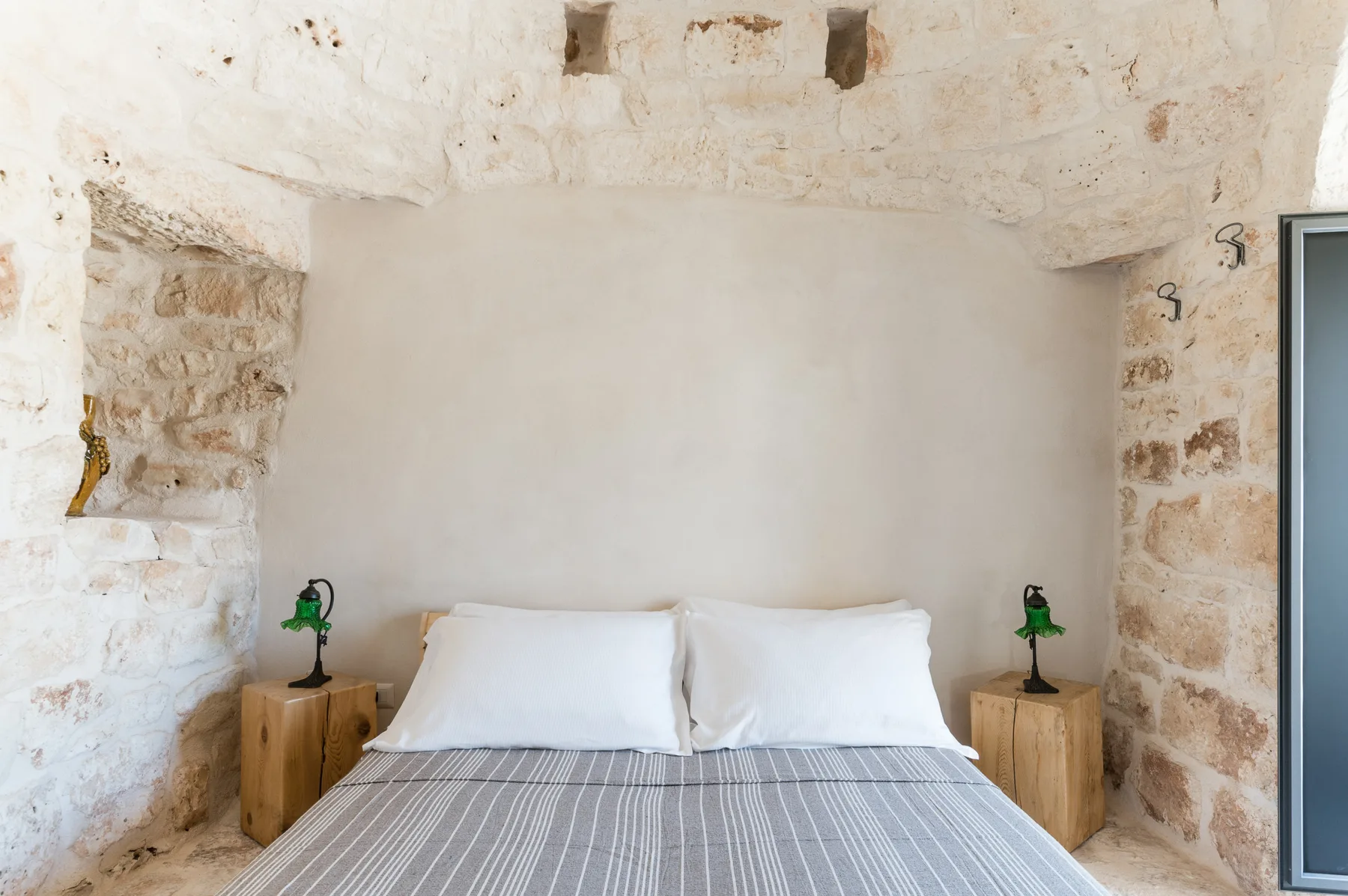 A bedroom with a bed between two wooden bedside tables.