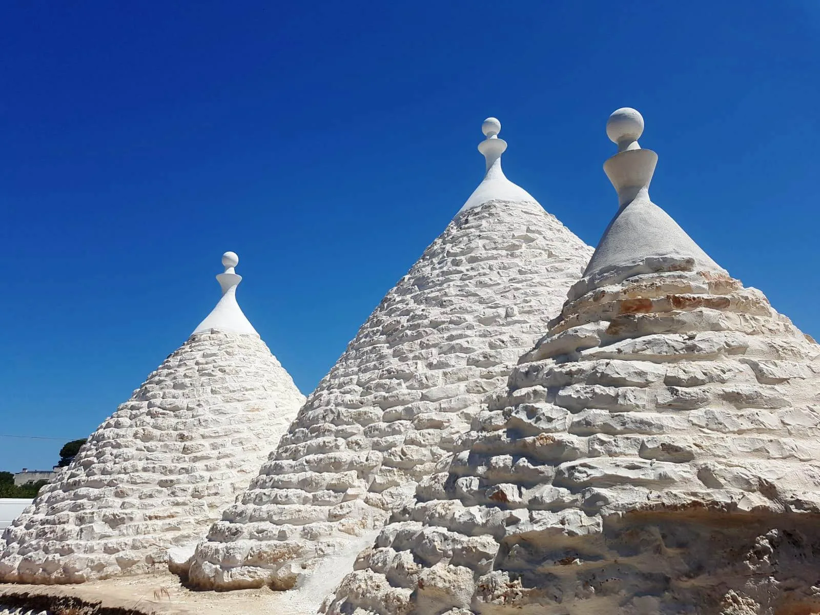 White conical stone roofs rise against a clear blue sky.