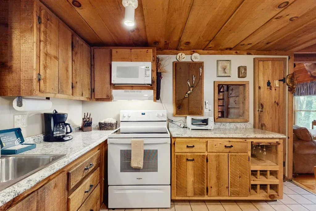 Una cocina revestida de madera con estufa, encimera y armarios de madera.