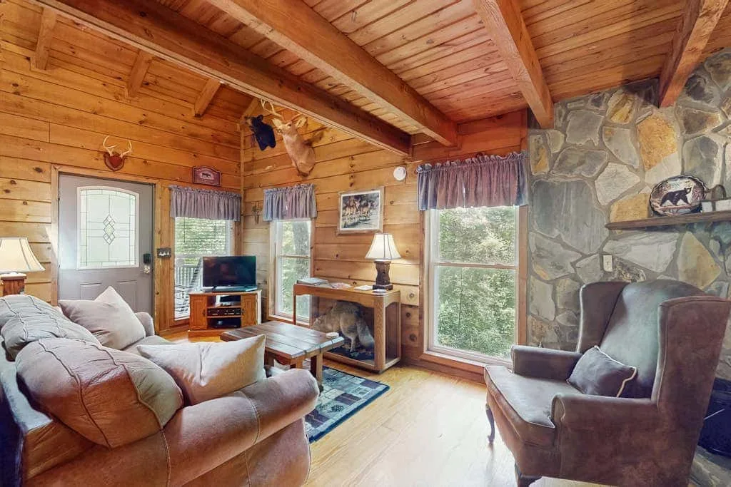 Una sala de estar revestida de madera con asientos, ventanas y una chimenea de piedra.