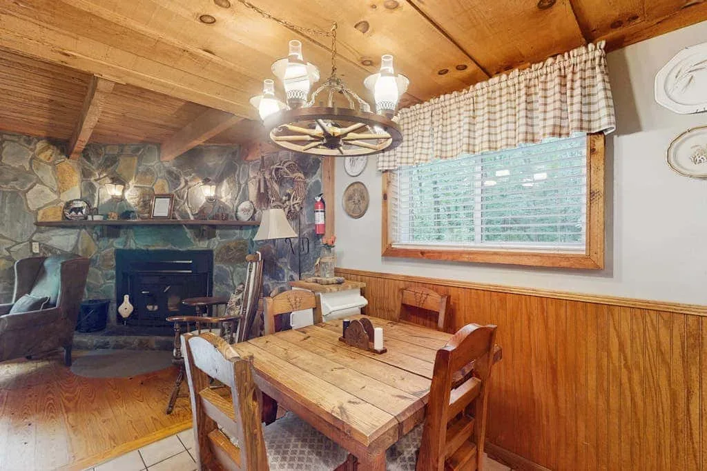 Un comedor rústico con una mesa de madera junto a una chimenea de piedra.
