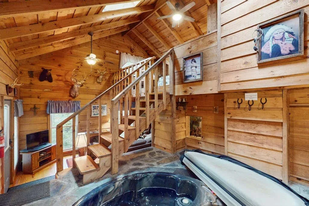 Una habitación revestida de madera con una escalera y una gran bañera de hidromasaje.