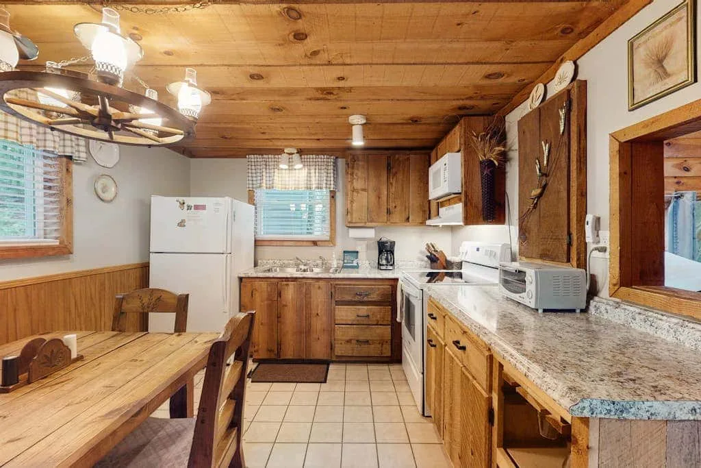 Una cocina rústica con gabinetes de madera, encimeras y una mesa de comedor.