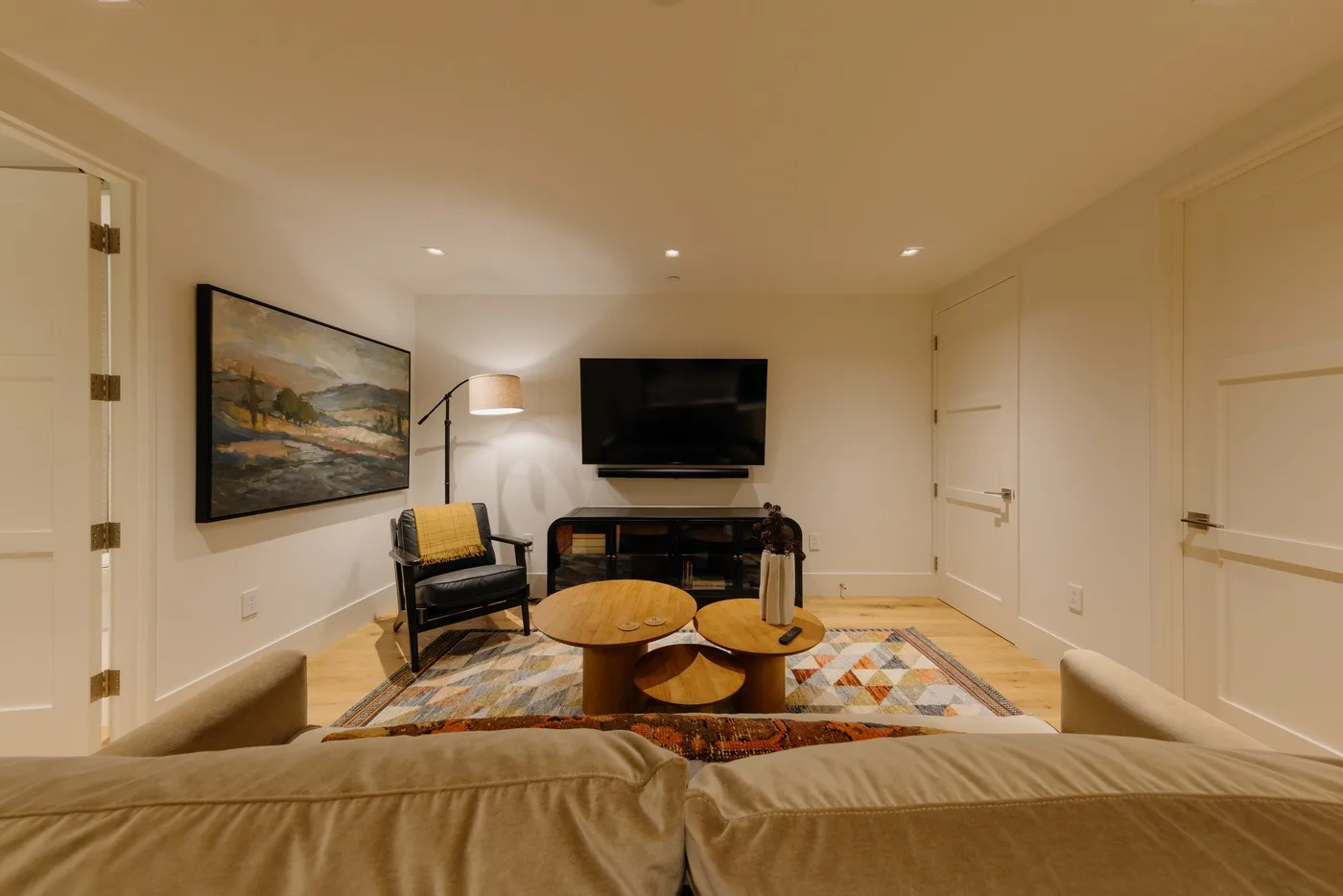 A living room with seating, a wall-mounted television, and a colorful area rug.
