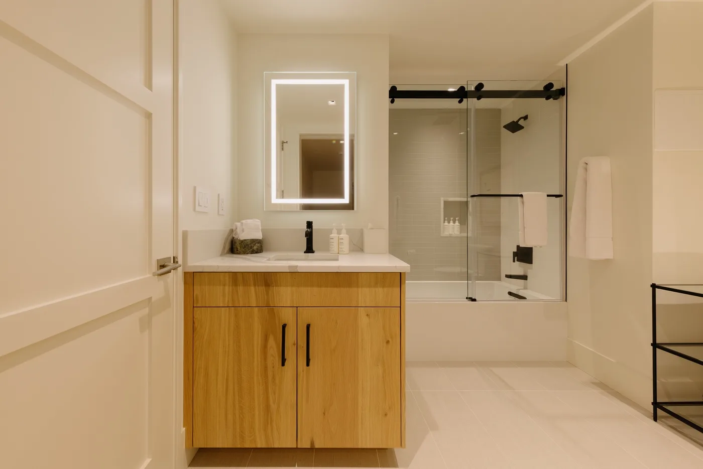 A bathroom vanity and mirror face a glass-enclosed shower.