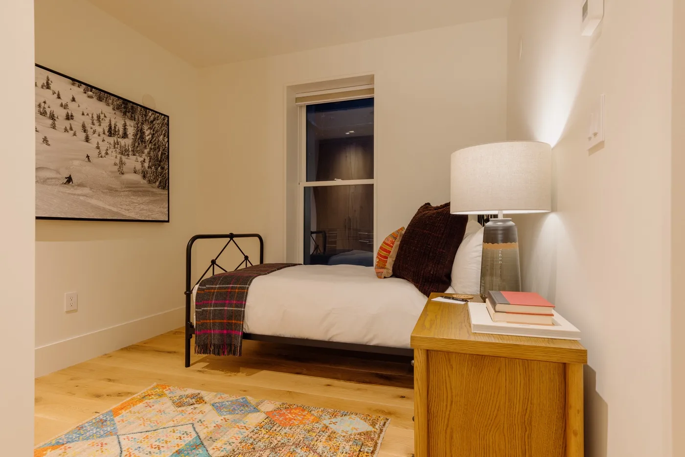 A bedroom with a bed, bedside table, and framed wall art.
