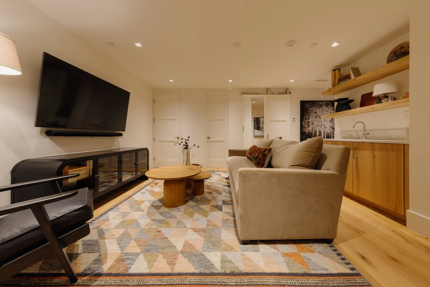A living room with seating, a television, and a kitchenette along one wall.