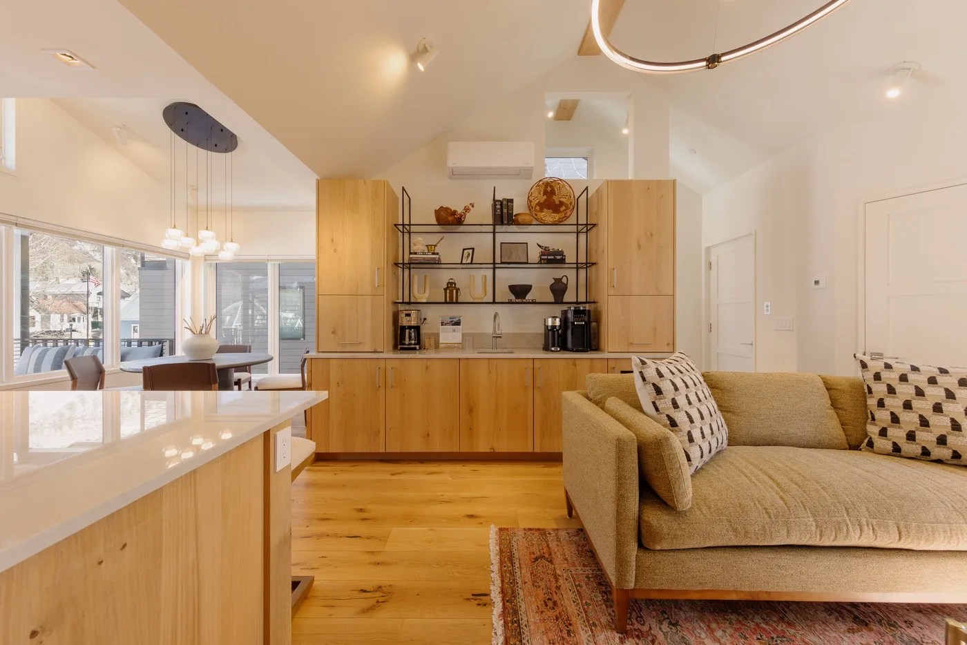 An open-plan kitchen and living area features wooden cabinetry and a beige sofa.