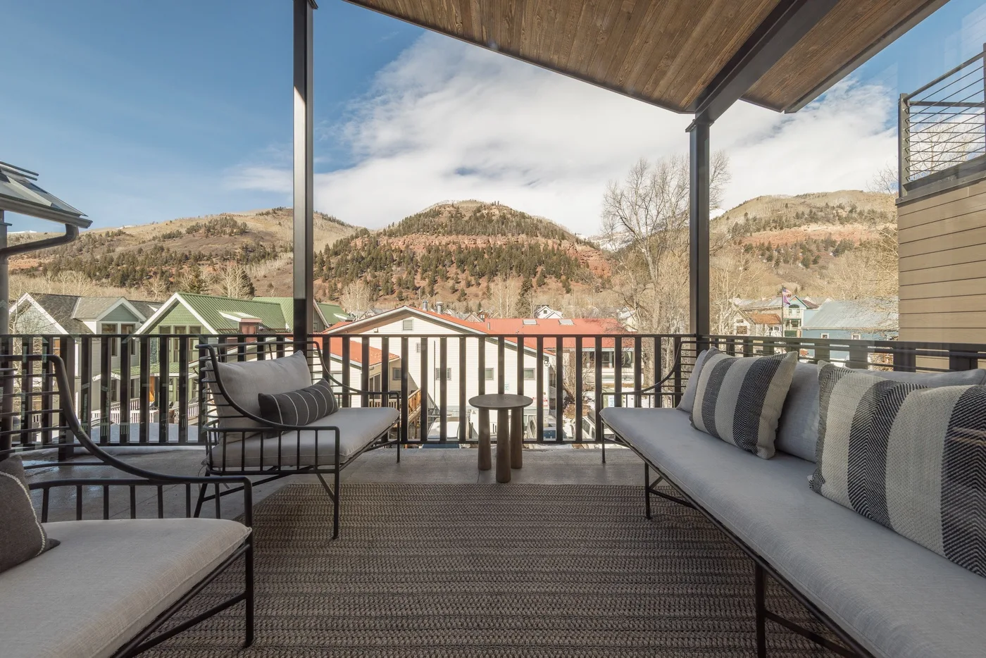 A covered outdoor seating area overlooks nearby buildings and a wooded hillside.