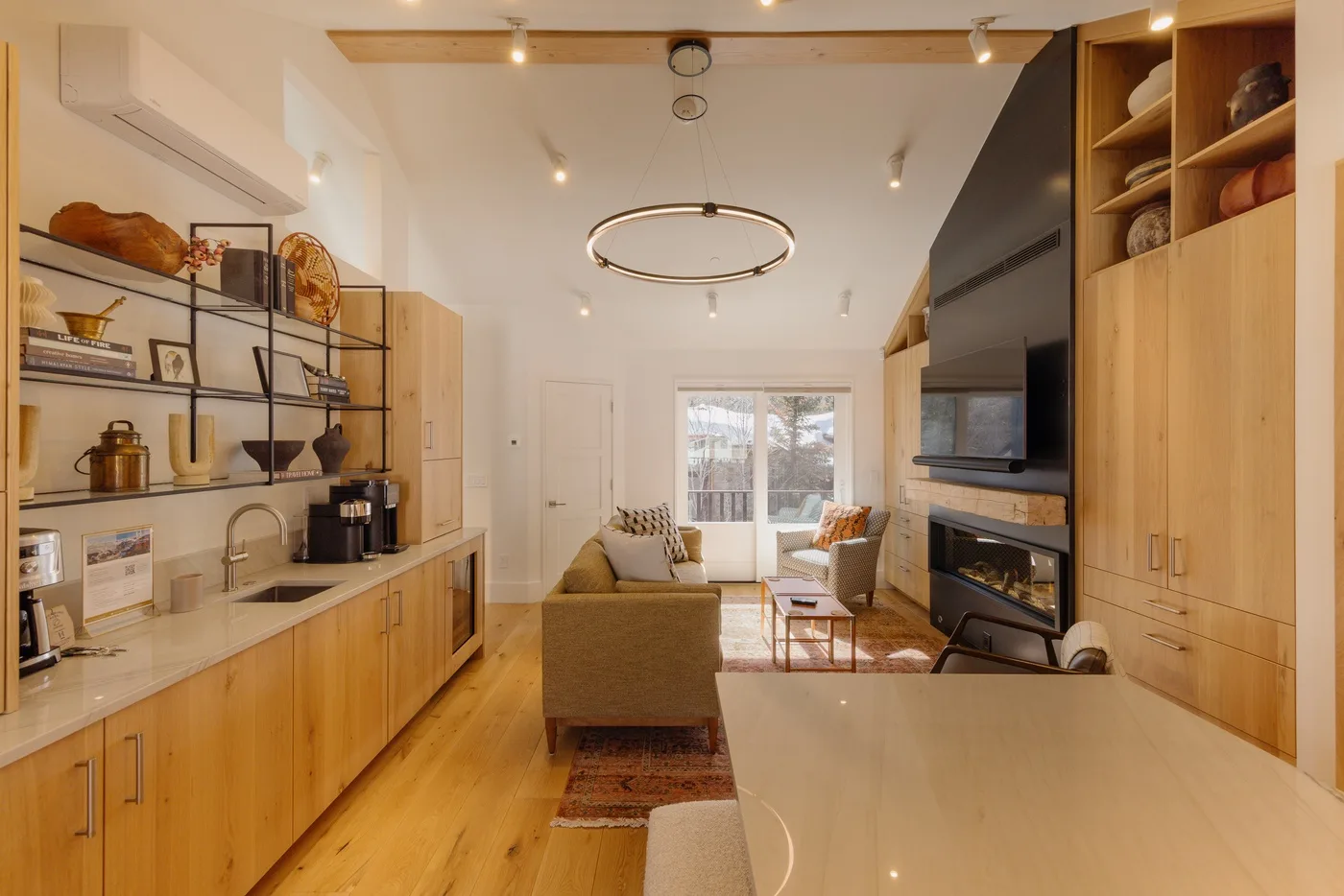 A bright open-plan living room with a kitchen counter and seating area.