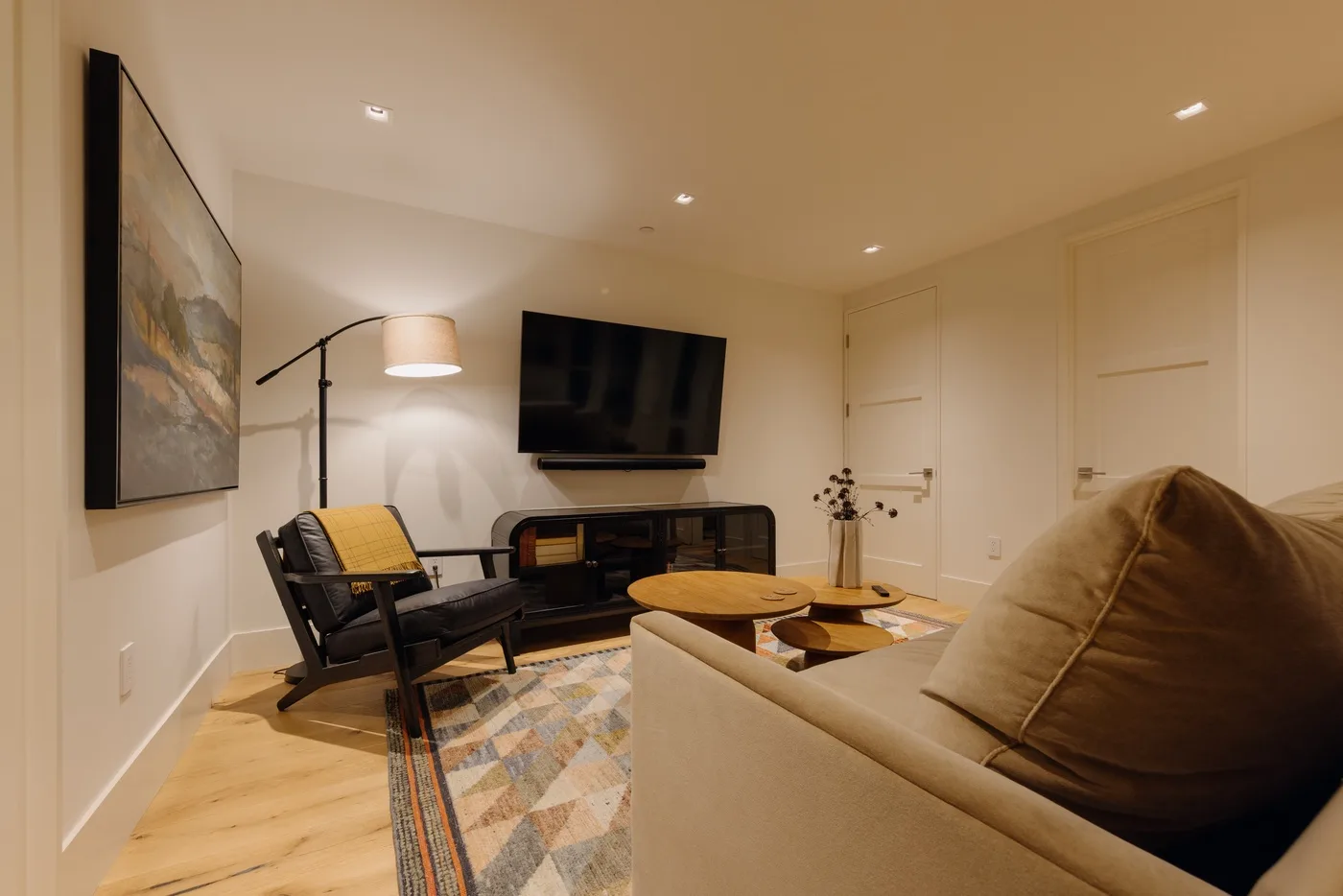 A living room with seating, a television, and a colorful area rug.