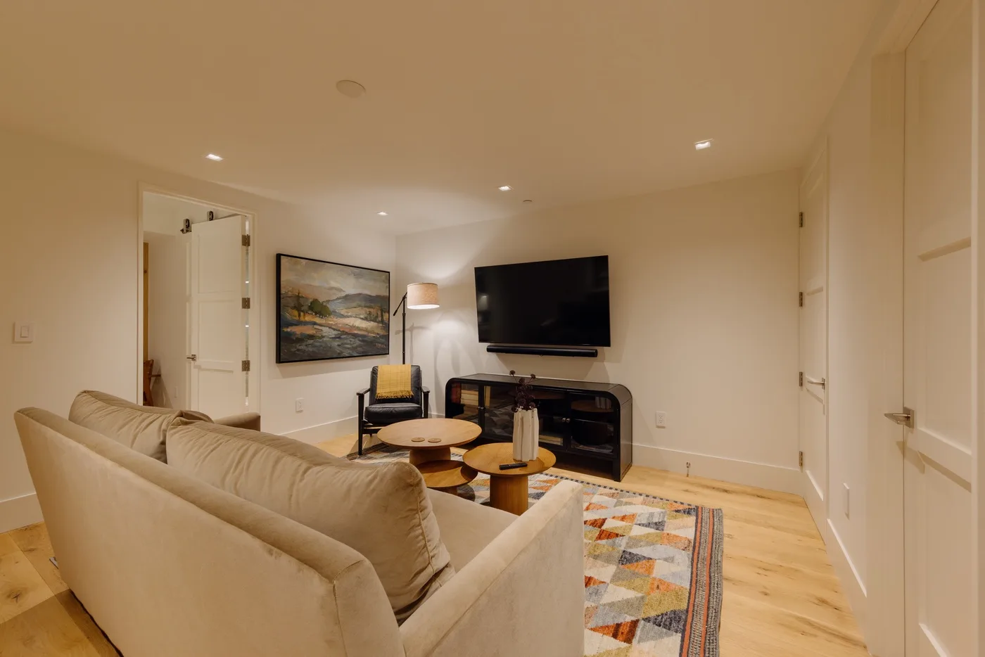 A living room with a television above a fireplace and seating around a coffee table.