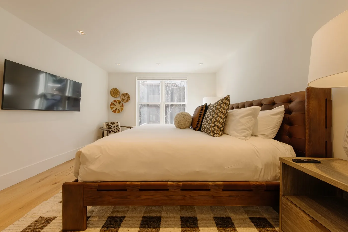 A bedroom with a large bed, patterned pillows, and a window.