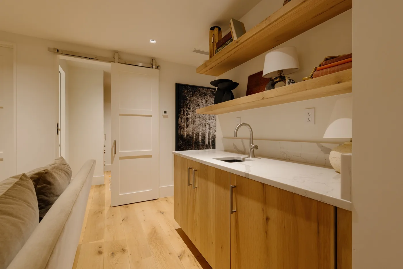 A compact kitchenette with wooden cabinetry and a sink beside a narrow seating area.