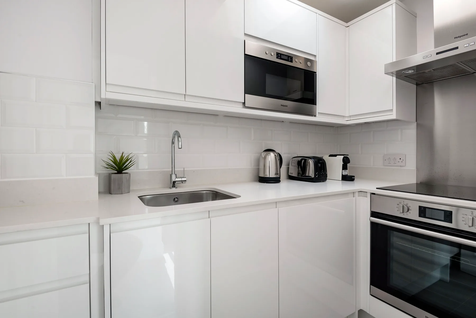 A bright kitchen with white cabinets, countertop appliances, and a built-in oven.