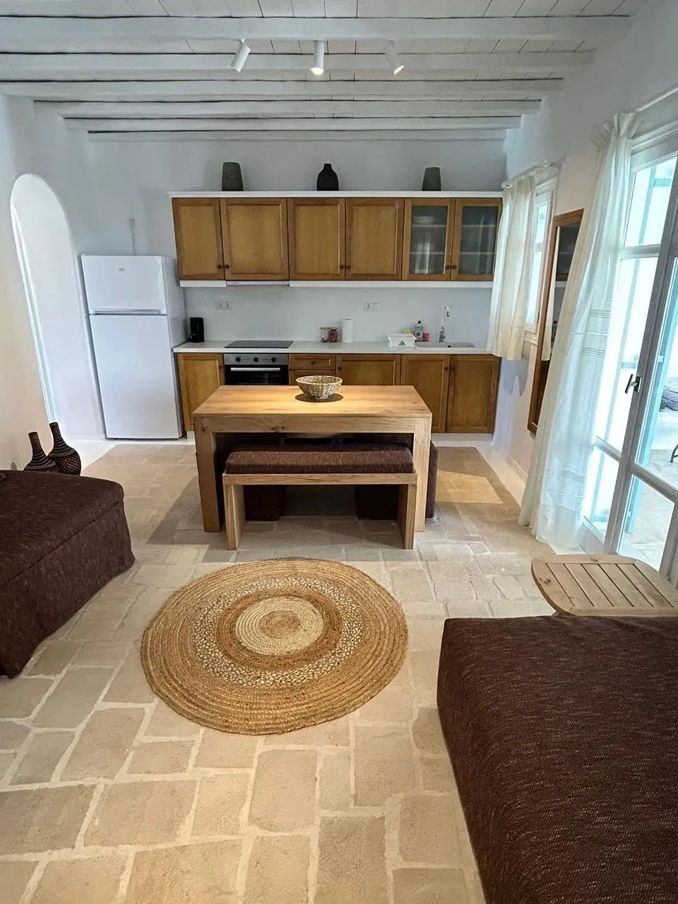 Una luminosa sala con comedor se conecta con una cocina compacta con gabinetes de madera.