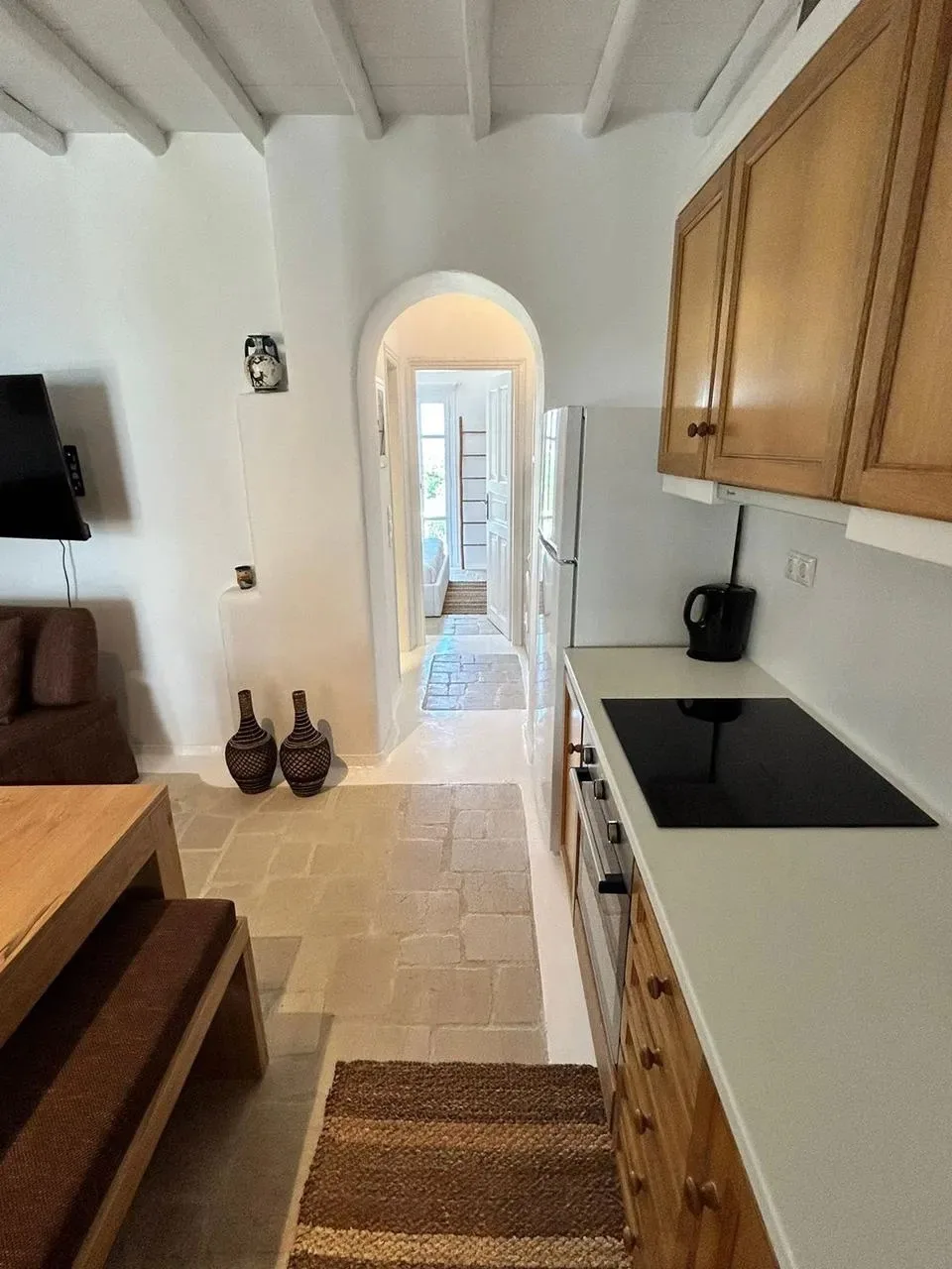 Una cocina pequeña y zona de estar dan a un pasillo luminoso con arco.