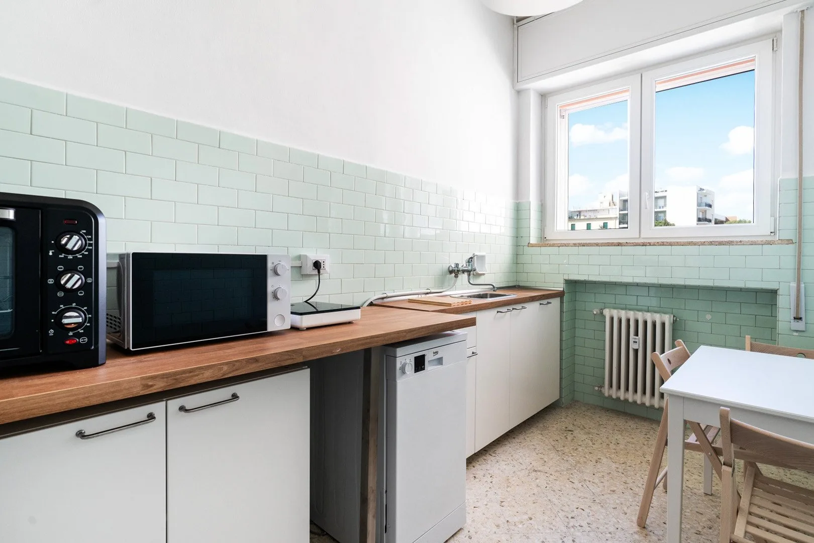 A bright kitchen with wooden countertops, appliances, and a small dining table.
