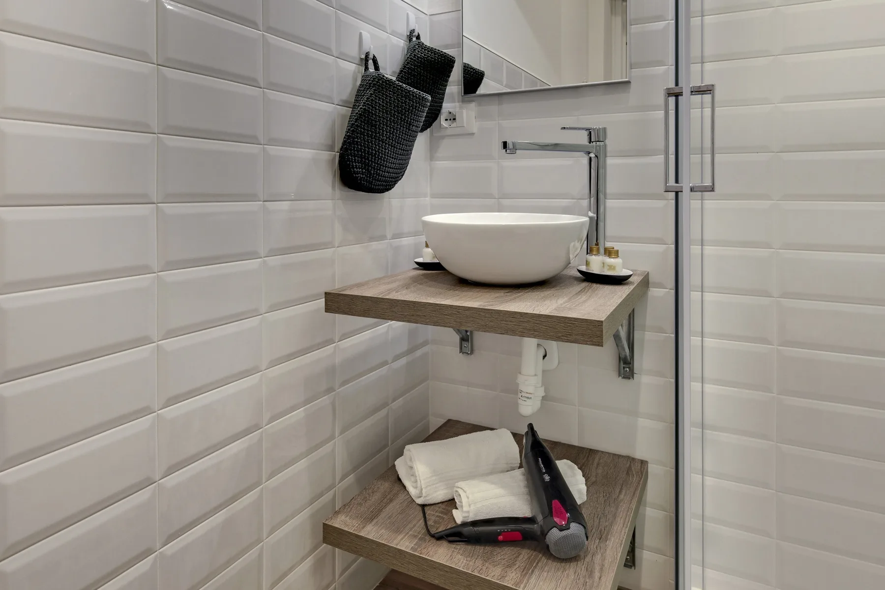 Un baño alicatado con un lavabo sobre encimera y una mampara de ducha de vidrio.