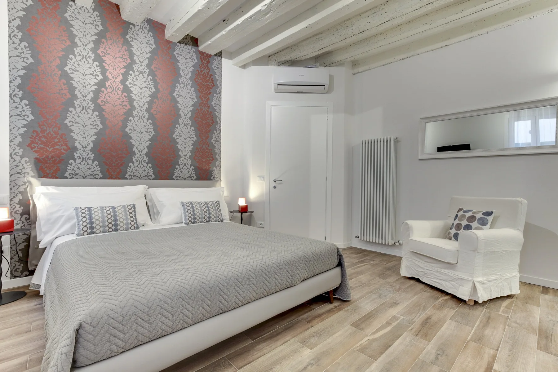 Un dormitorio con una cama grande, una pared decorativa estampada y un sillón blanco.
