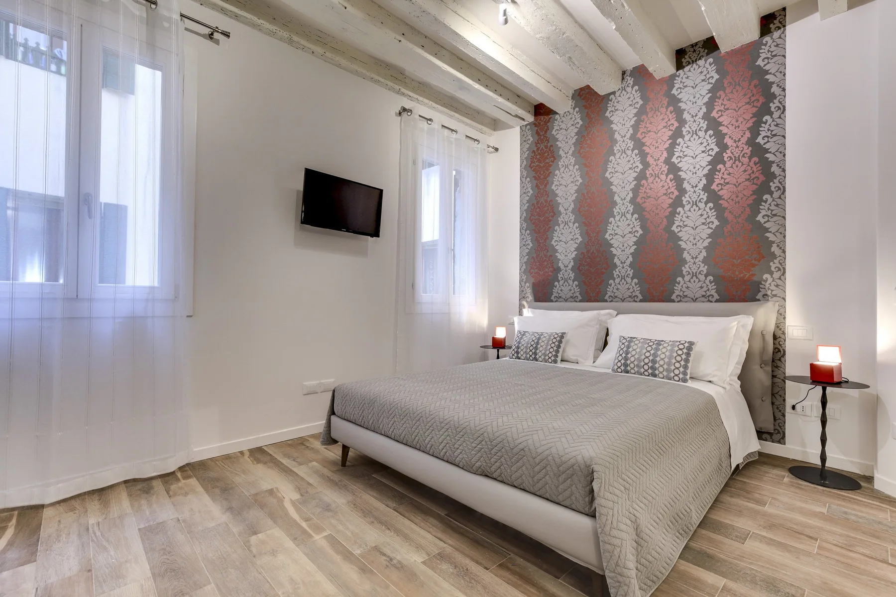 Un dormitorio con una cama arreglada y papel tapiz estampado detrás del cabecero.