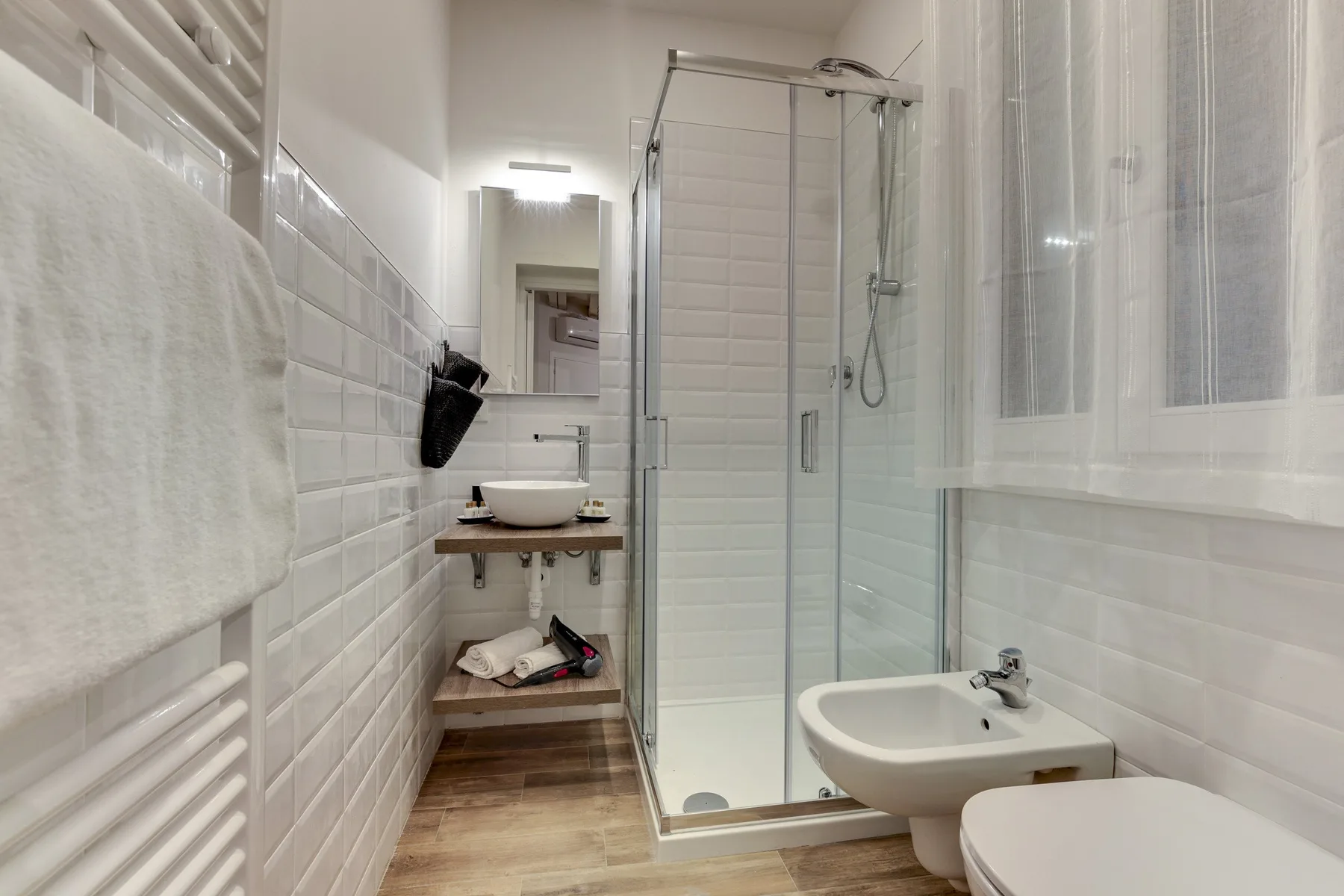 Un baño alicatado con ducha de cristal, lavabo e inodoro.