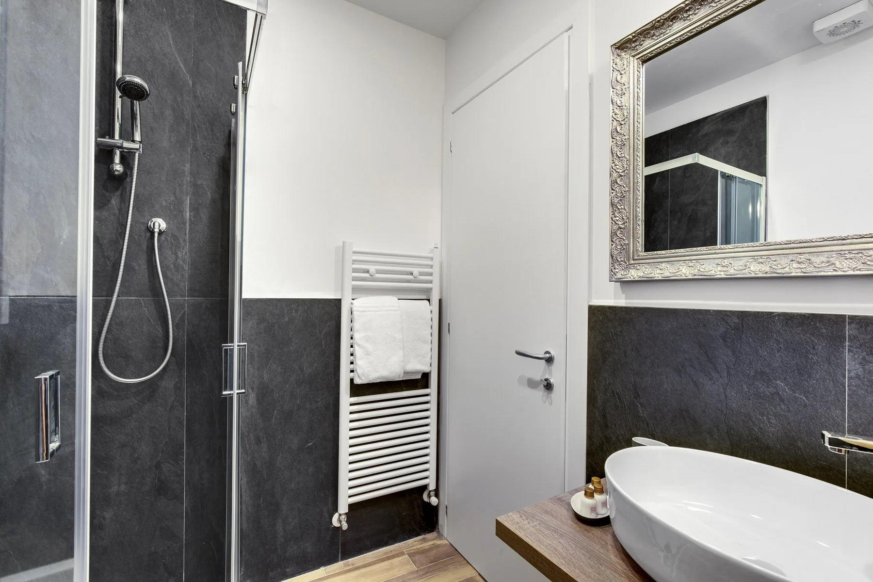 Un baño moderno con ducha de vidrio, toallero calefactable y lavabo.