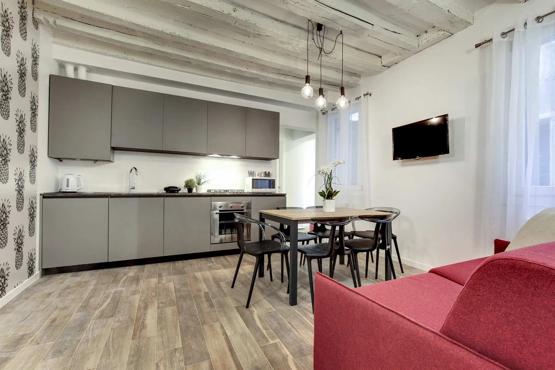 Una cocina abierta con comedor y un sofá rojo en primer plano.