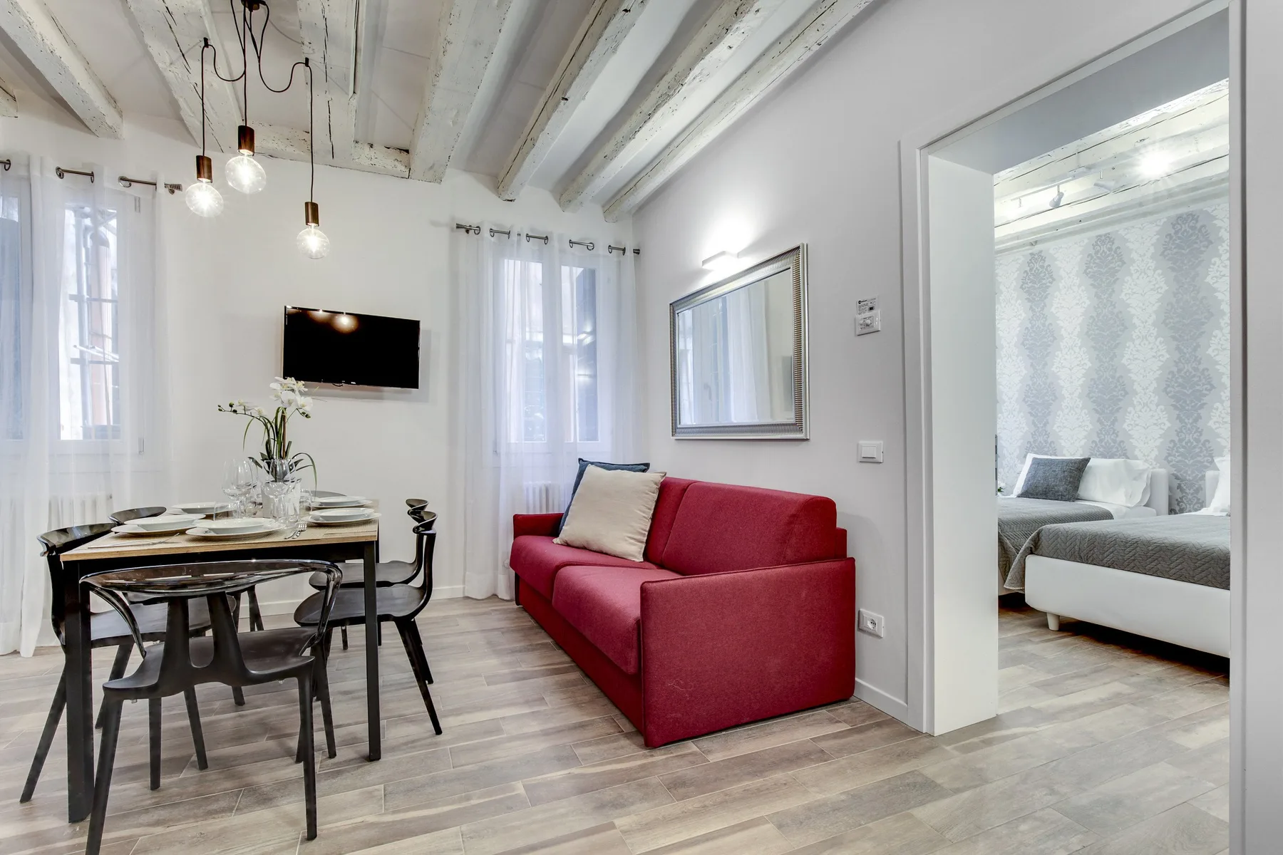 Una luminosa sala de estar y comedor con un sofá rojo junto a una mesa de comedor.
