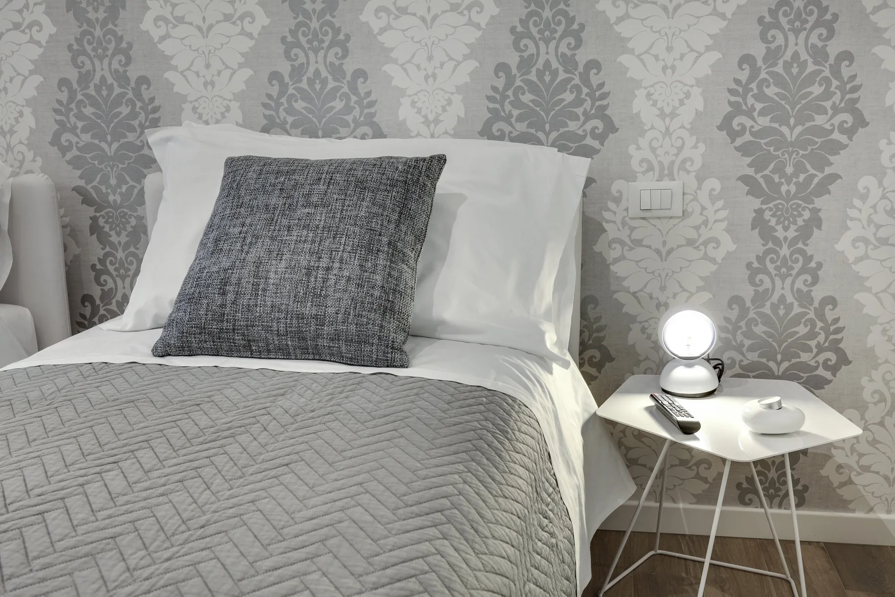 Un dormitorio con una cama, ropa de cama estampada y una mesita de noche.