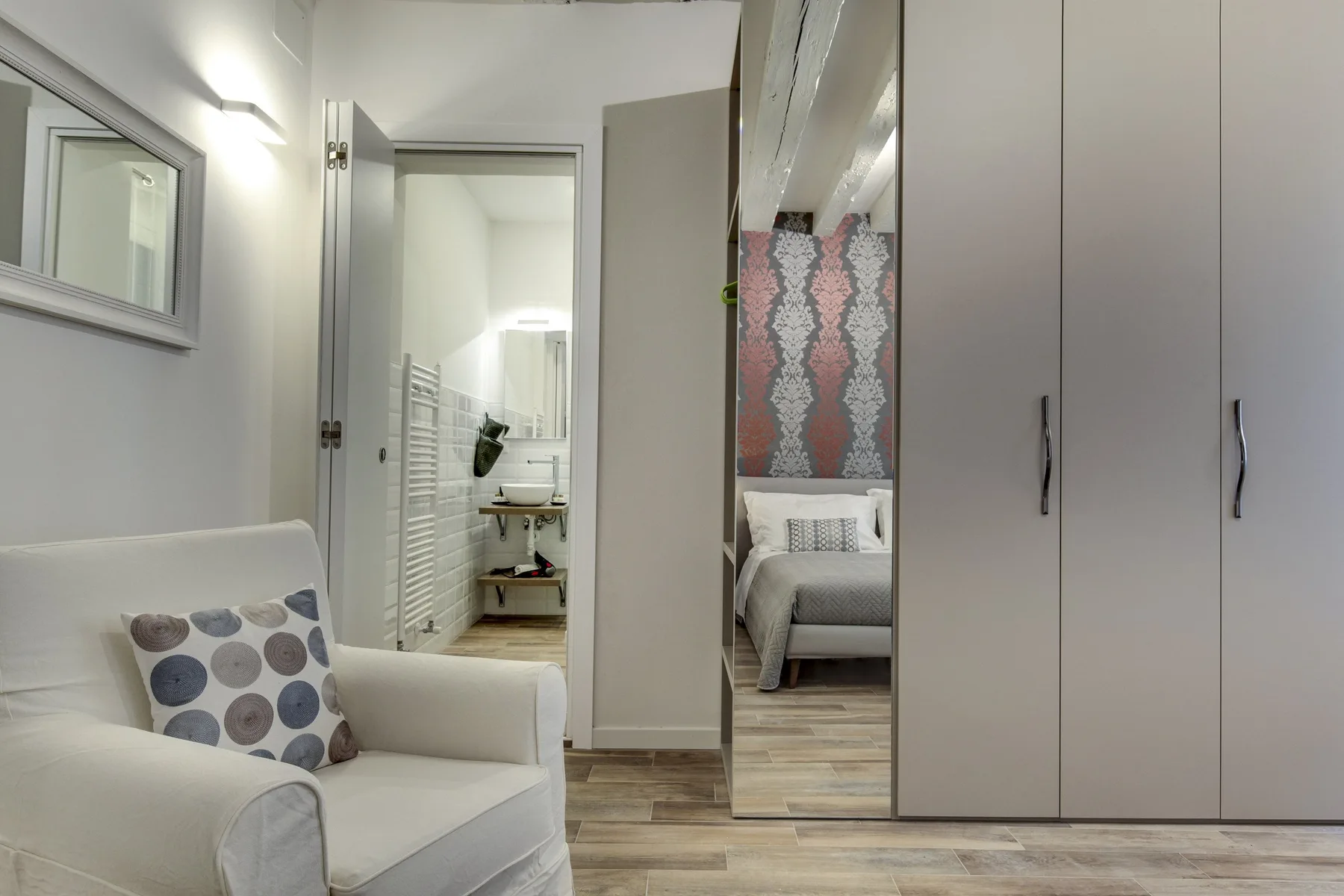 Un dormitorio luminoso con una zona de descanso y puertas de armario con espejo.