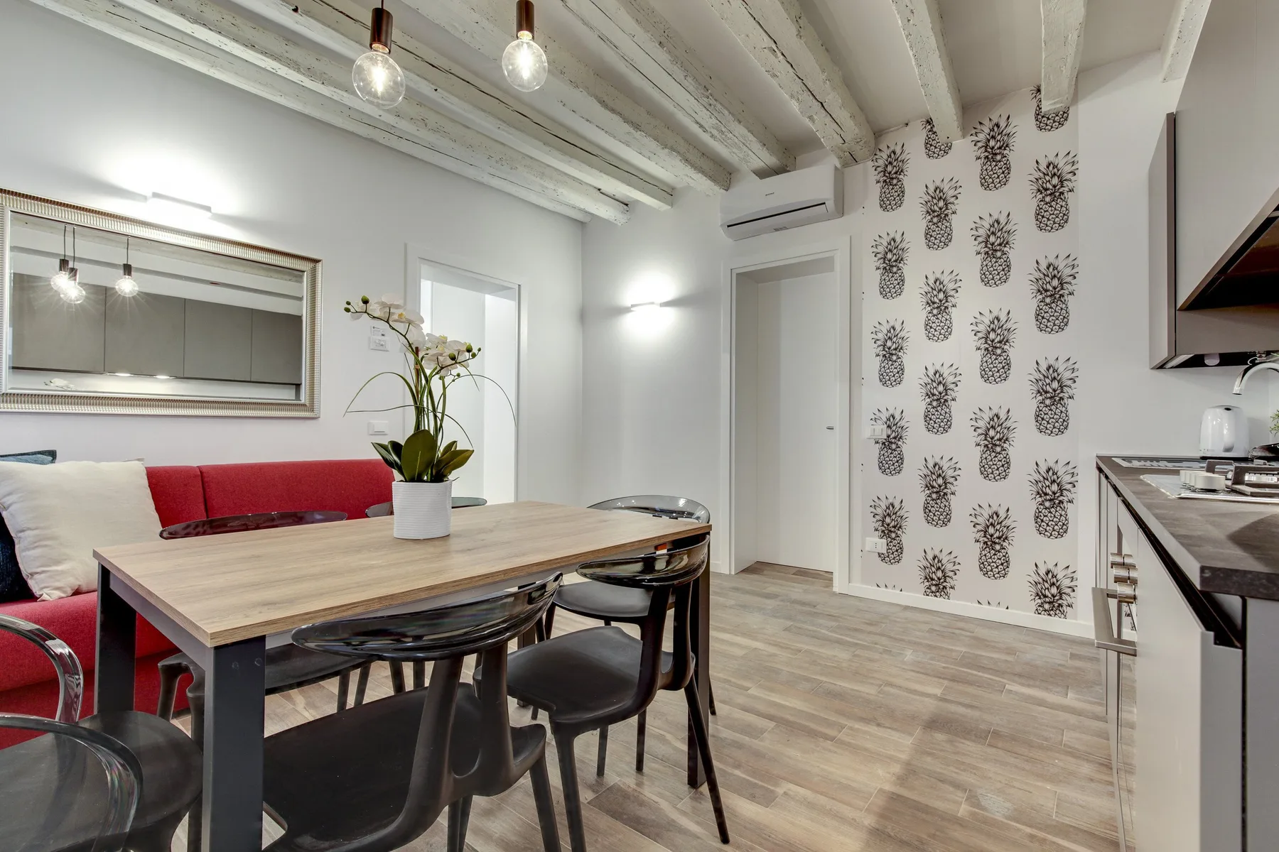 Un comedor con una mesa de madera, asientos y papel tapiz estampado.