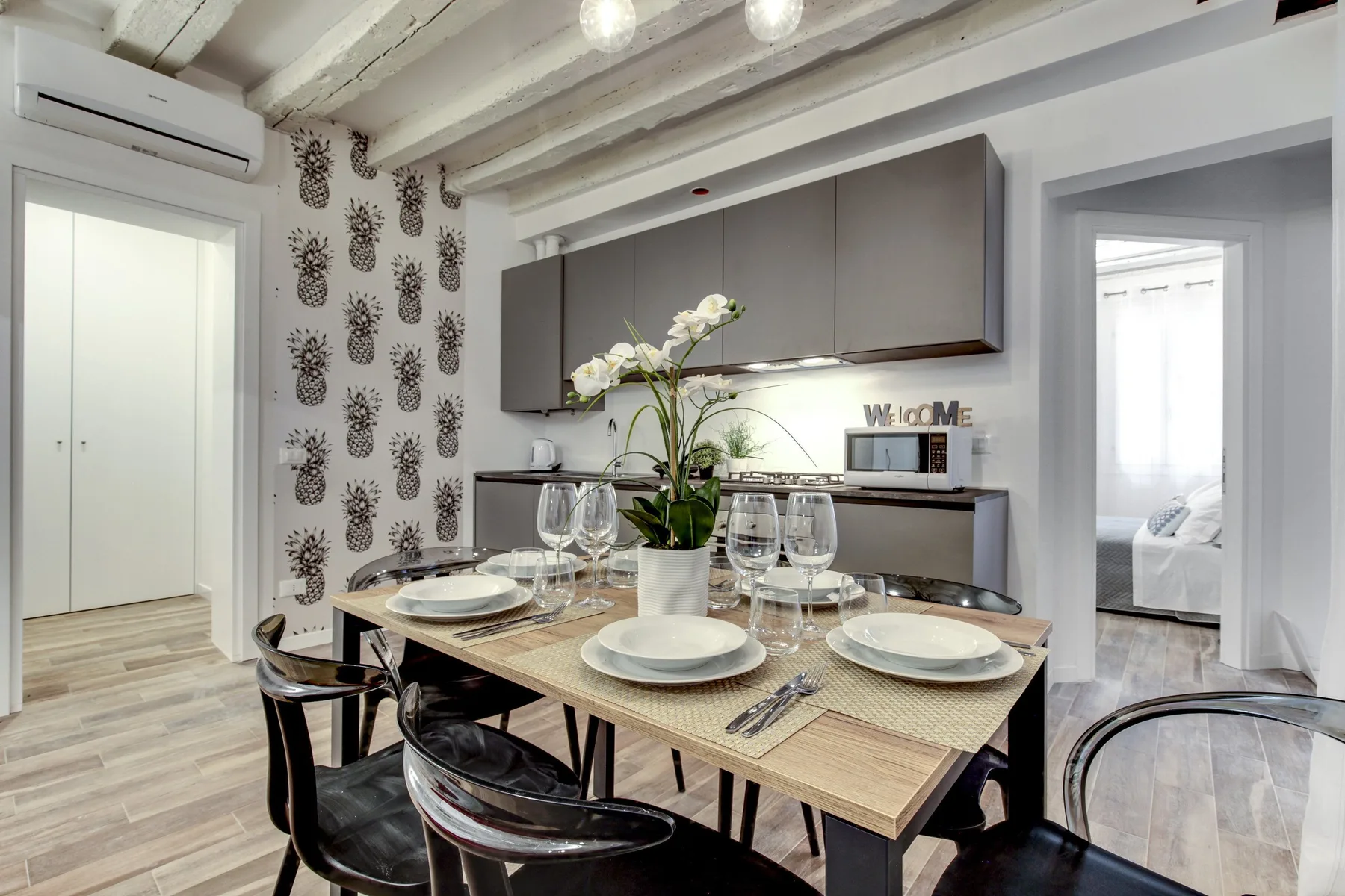 Un comedor con la mesa puesta y una cocina compacta al fondo.