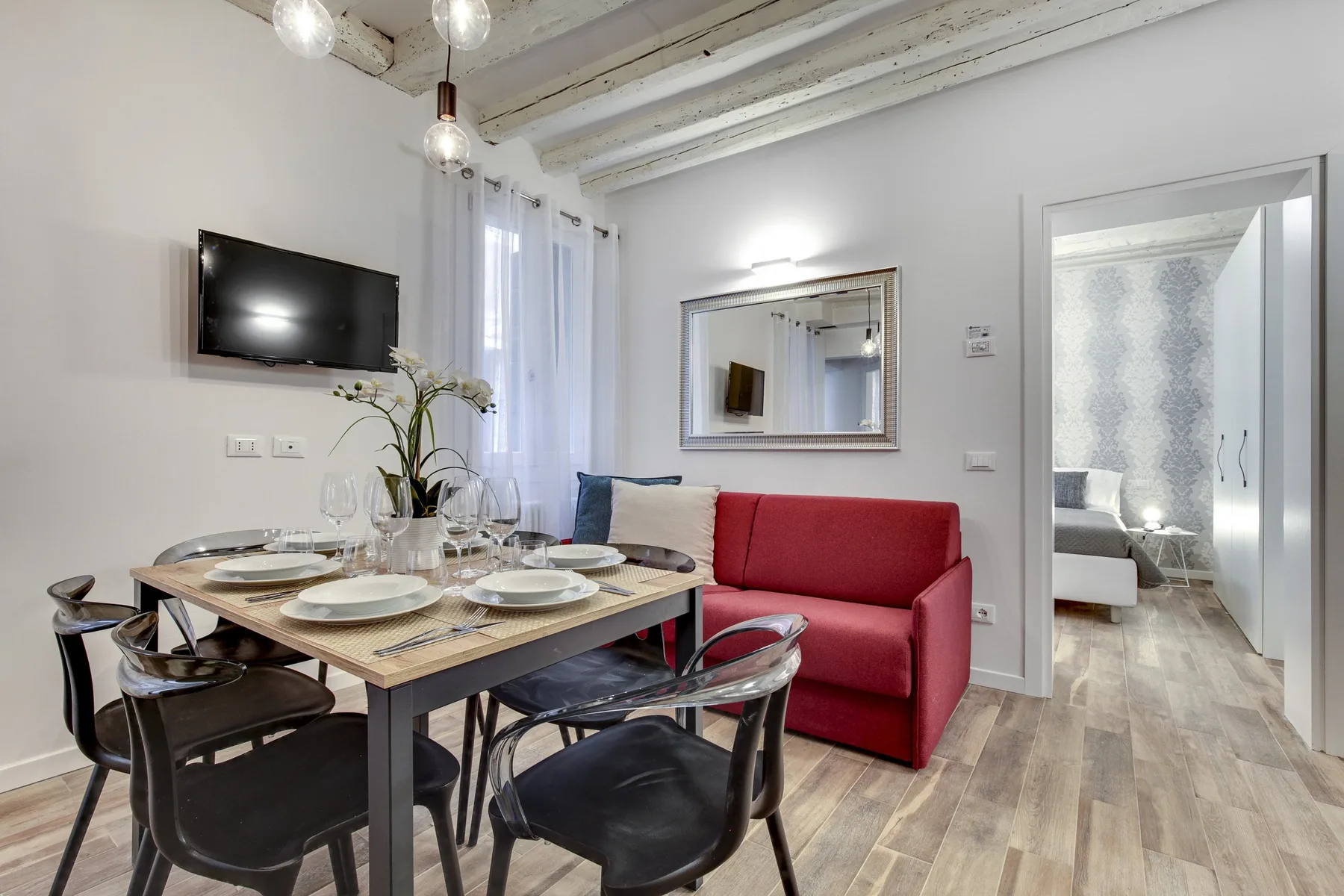 Una luminosa zona de comedor y estar con una mesa puesta junto a asientos rojos.