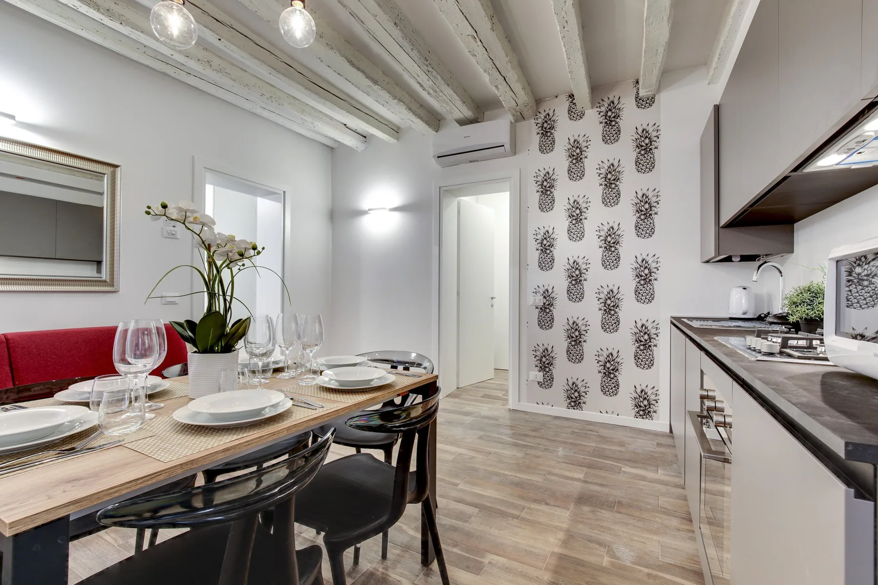 Comedor junto a una cocina, con la mesa puesta y una pared estampada.