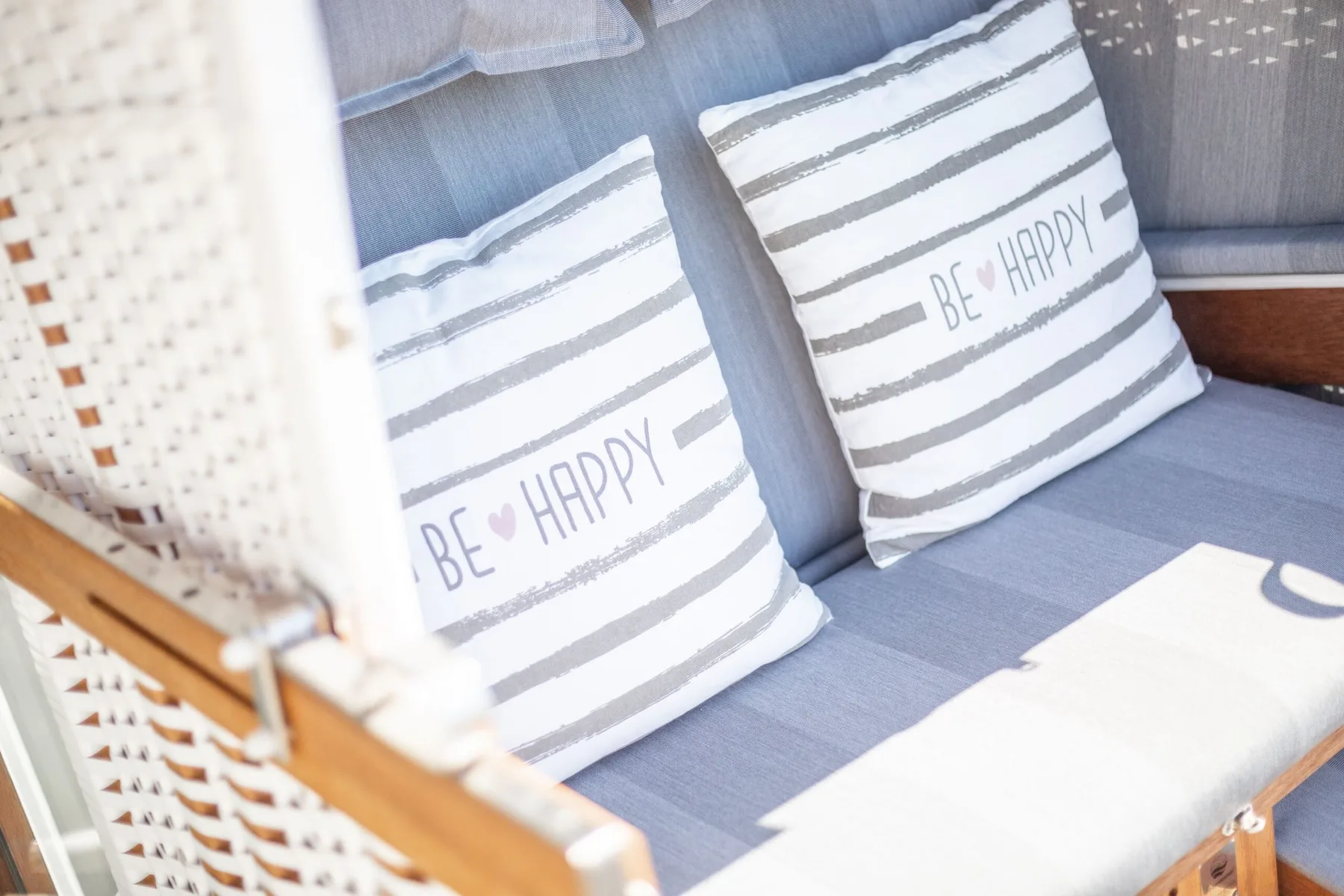 A cushioned seating area with striped pillows sits beside a woven panel.