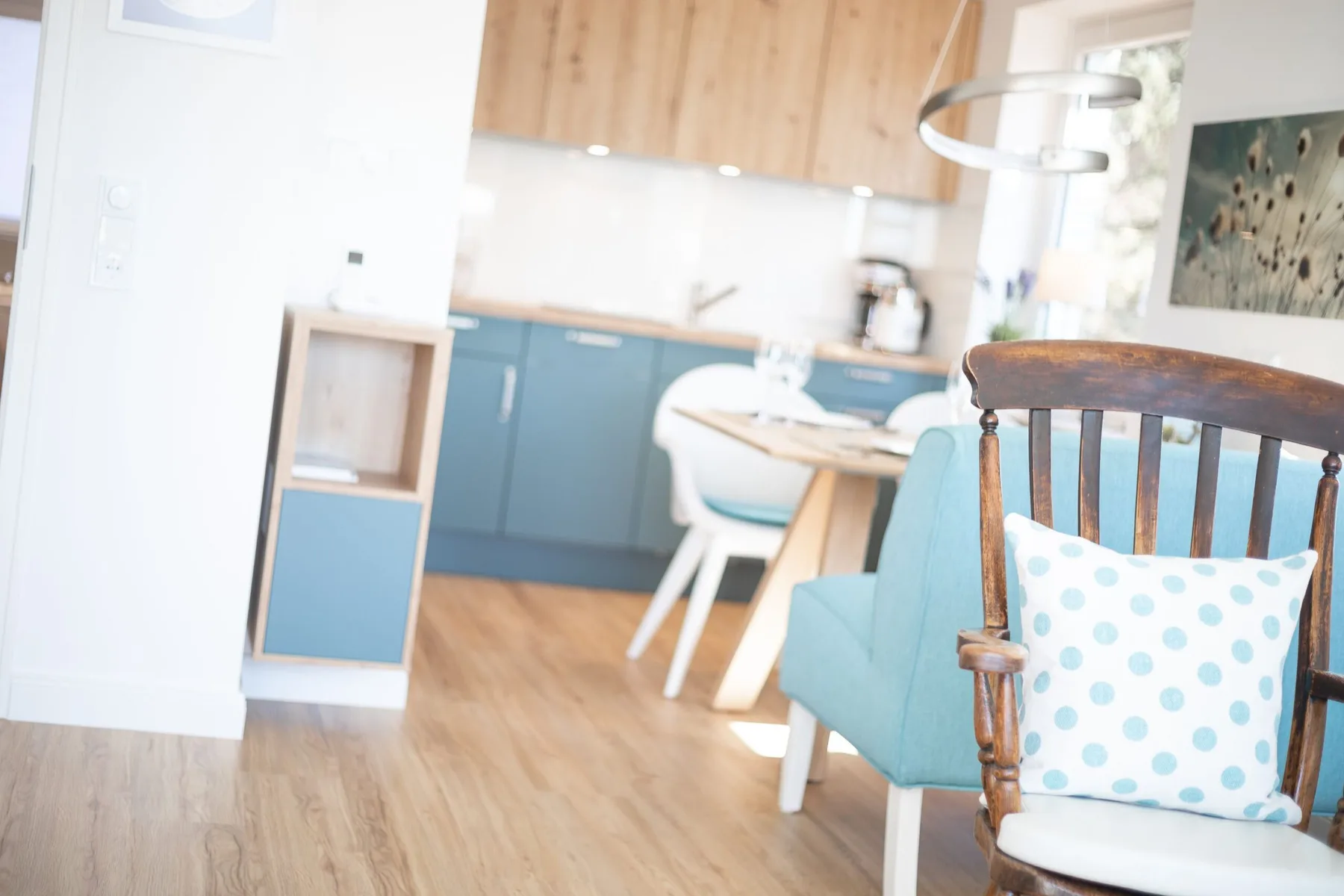 A dining area with blue seating and a light wood kitchen behind it.