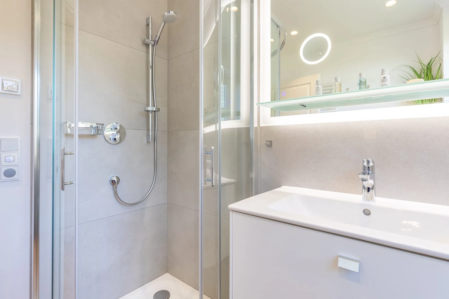 A bright bathroom with a glass shower and a white sink vanity.